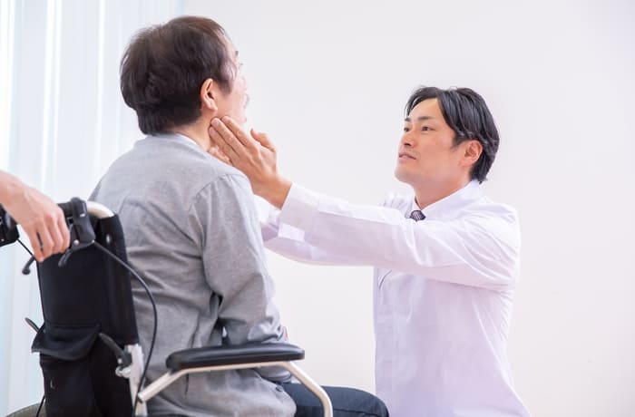 入れ歯が合わない患者様の口腔内を診察する歯科医師
