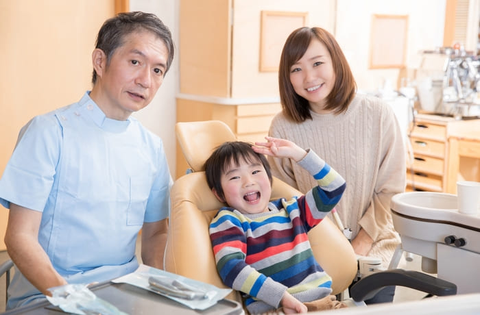 永久歯がなかなか生えてこない子どもの歯並びについて歯科医師に相談する親子