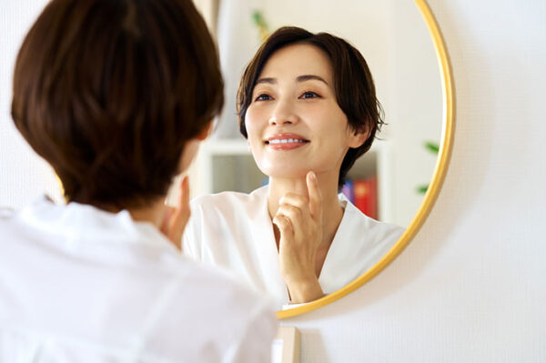 鏡の前で自分の歯の白さを確認する女性