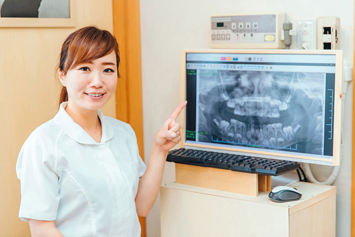 従来のレントゲン写真を指差しする女性歯科医