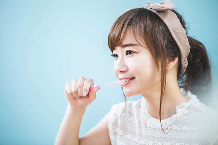 手で歯ブラシを持って歯を磨く女性