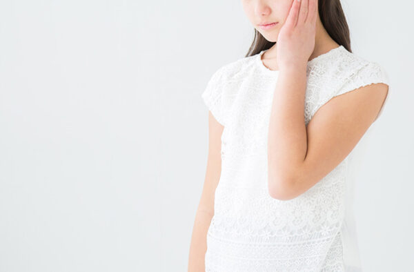 強い歯の痛みや腫れを感じて頬を押さえる女性