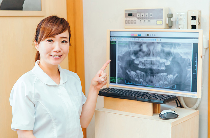 歯のレントゲン画像を使って根管治療について説明する歯科スタッフ