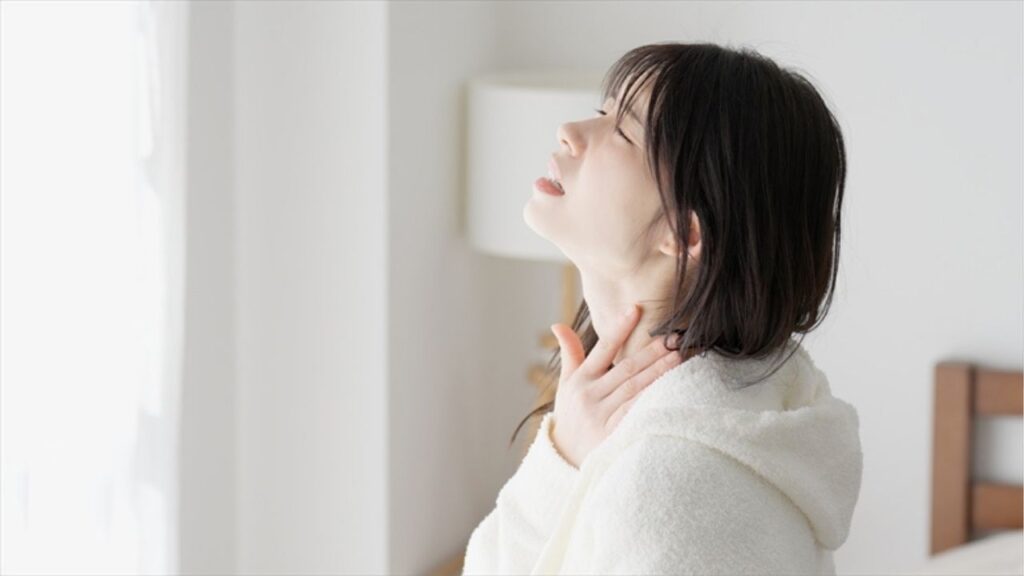 寝起きに喉をおさえる女性