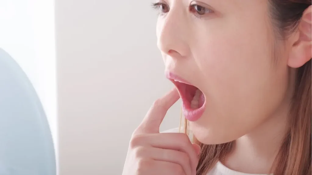 鏡で口の中を見ている女性