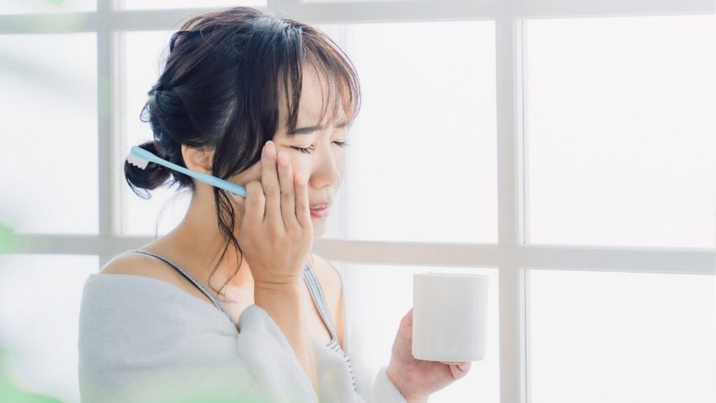 女性が頬に手をあてて顔をゆがめている