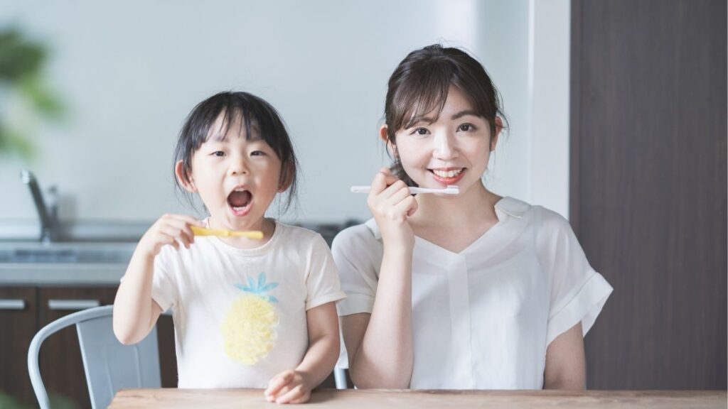 歯磨きをするポーズをとっている女性と女の子