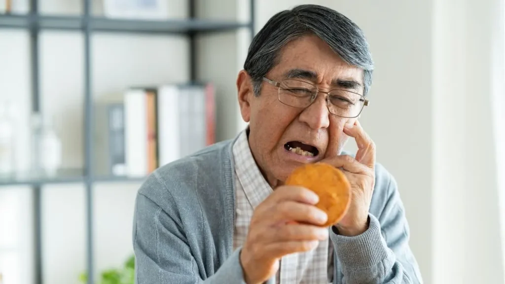 せんべいを手に持って顔を歪める男性