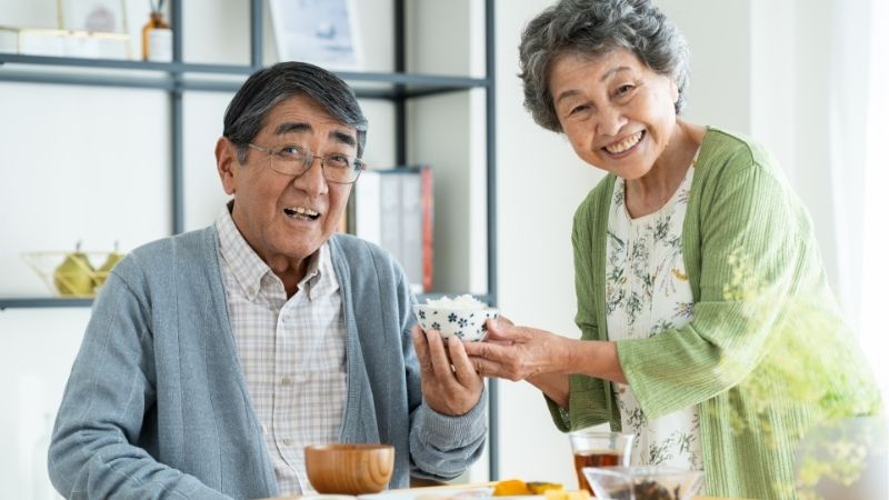 笑顔でお茶碗を持つ高齢夫婦
