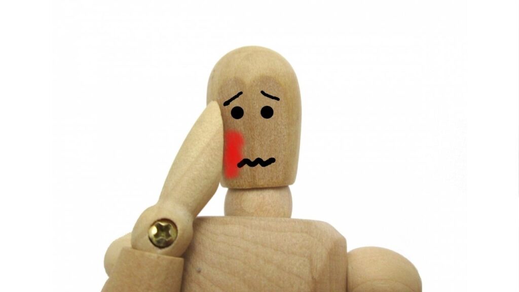 赤くなった頬を手で抑える木の人形