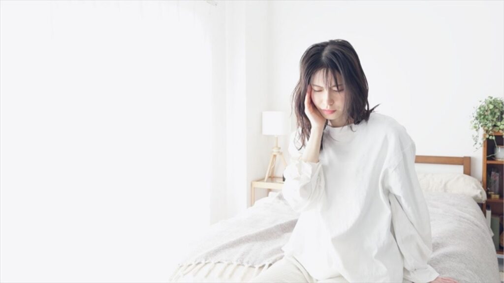 ベットで頬を抑える女性